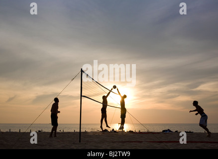 junge Männer spielen Beach-Volleyball bei Sonnenuntergang am Karon Beach in Phuket - Thailand Stockfoto