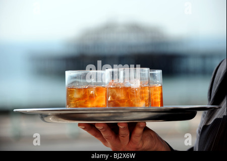 Tumbler Gläser Whisky mit Klumpen von Eiswürfeln auf einem Tablett vor West Pier Brighton Seafront von hand gehalten Stockfoto