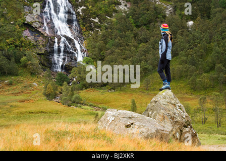 Ein Wanderer bewundert den Blick auf einen Wasserfall in der Nevis-Range in der Nähe von Ben Nevis, Schottland Stockfoto