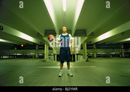 Mann hält Basketball auf Parkplatz Stockfoto