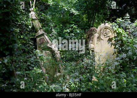 Efeu Unterholz in Nunhead Friedhof, überwucherte Gräber und Grabsteine unterliegen. Stockfoto