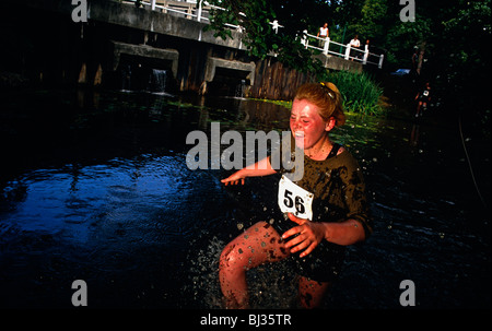 eine weibliche Officer Cadet an der Royal Military Academy Sandhurst plätschert durch ein Wasserhindernis während einem Dauertest unterzogen. Stockfoto