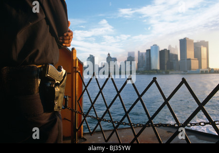 Ein bewaffneter Polizist in New York City Police Department (NYPD) steht Wache an der Front (der Bogen) von der Staten Island Ferry. Stockfoto