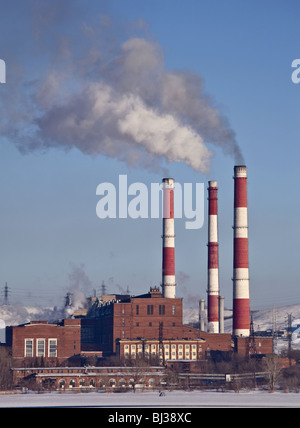 Fabrikgebäude mit drei rauchenden Schornsteinen Stockfoto