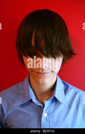 Ein 13 Jahre alter Junge mit langen Haaren, die seine Augen bedecken. Stockfoto