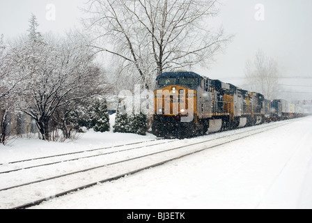 CSX Frachtzug Motor Fortschritte in Richtung Eisenbahn Kreuzung Kreuzung in starkem Schneefall. Stockfoto