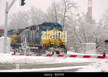 CSX Frachtzug Motor Fortschritte in Richtung Eisenbahn Kreuzung Kreuzung in starkem Schneefall. Stockfoto