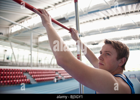 männlicher Athlet Einstellbalken Hochsprung Stockfoto