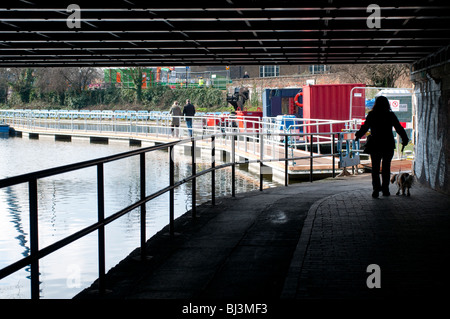 Frau zu Fuß einen Hund unter Brücke entlang Regents Canal, York Weg, Kings Cross, London, UK Stockfoto