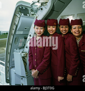 Vier weibliche Flugbegleiter tragen die Uniformen der Qatar Airways Stand in der offenen Tür von einem Airbus A319CJ Business-Jet. Stockfoto