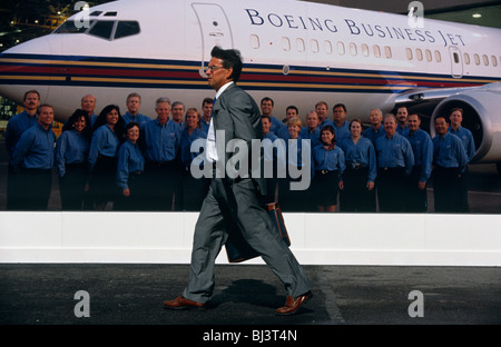 Ein Geschäftsmann eilt vorbei Boeing Firma Werbung Riesenposter während der Farnborough Air Show, England. Stockfoto