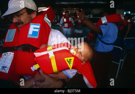 Vater und Sohn üben tragen Rettungsringe während einer Evakuierung Drill in den ersten paar Stunden ihrer Reise von Miami. Stockfoto