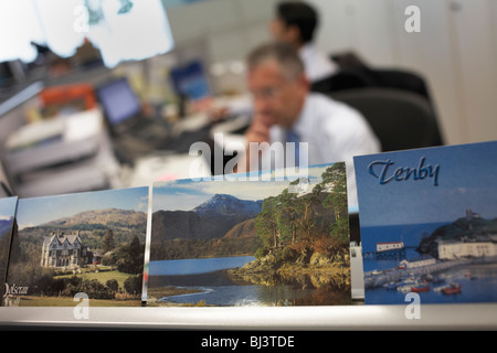 Mitarbeiter in einem zentralen London Büro arbeiten fleißig neben den Erinnerungen an Urlaub, die Kollegen und Freunde getroffen haben Stockfoto