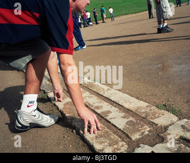 Touristischen hockt auf original 4. Jahrhundert Marmor Startlinie im antiken Olympia Leichtathletik-Laufbahn, 600 Yards ging von Herkules. Stockfoto