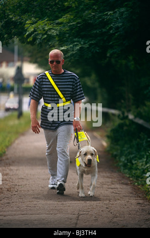 Mit abgedunkelten Brille, Spaziergänge ein ungesehen Mann s Pflaster in der Nähe der Blindenhunde für blinde Vereins. Stockfoto