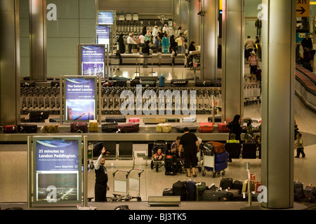 Flugpassagiere, die Erwartung der Ankunft des Gepäcks im Gepäck zurückfordern Hall in der Ankunftshalle des Flughafens Heathrow T5. Stockfoto