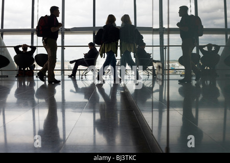 Silhouetten der abfliegenden Passagiere sind gegen die starken Tageslicht aus den riesigen Fenstern gesehen, die nach außen zu stellen. Stockfoto
