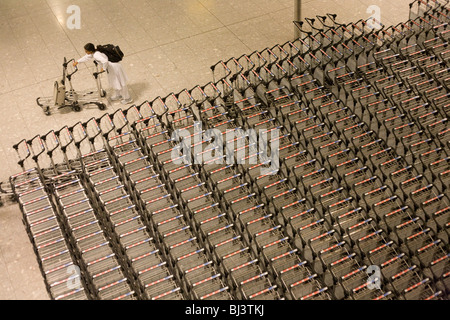 Fluggesellschaft Passagiere Kämpfe, zwei Wagen im Gepäck zu trennen zurückfordern Hall in der Ankunftshalle des Flughafens Heathrow. Stockfoto