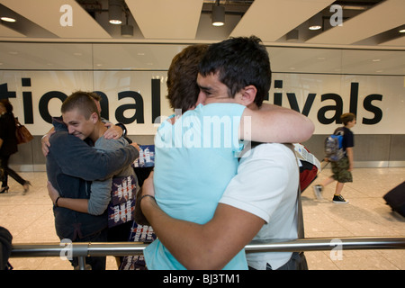 Mütter und Söhne umarmen emotional in der internationalen Ankünfte Hall von Heathrow Airport Terminal 5 Flughafen. Stockfoto