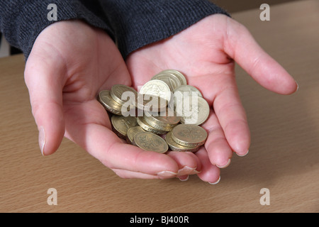 Weibliche Hände halten einige englische Pfund-Münzen. Stockfoto