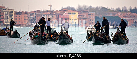 Eine Gruppe von Gondeln und Gondolieri, die ihre Passagiere entlang des Canal Grande in Venedig, Veneto, Italien Stockfoto