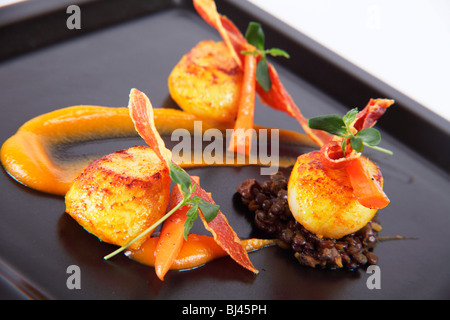 Trio von Jakobsmuscheln auf Curry Linsen, Butternut-Kürbis-Püree und knusprigem Parmaschinken Stockfoto