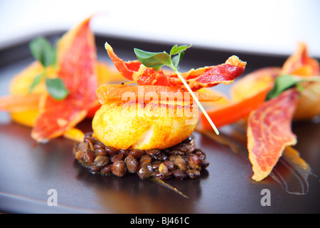 Trio von Jakobsmuscheln auf Curry Linsen, Butternut-Kürbis-Püree und knusprigem Parmaschinken Stockfoto