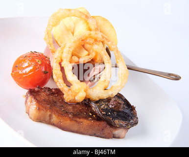 Gebratenes Entrecôte mit Pommes Frites und Tempura Teig Zwiebelringe Stockfoto