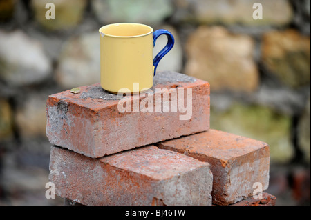 Ein Baumeister Becher Tee auf einem Stapel von aufgearbeiteten roten Ziegeln UK Stockfoto