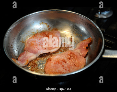 Zwei Speckscheiben Speck in einer Pfanne braten Stockfoto