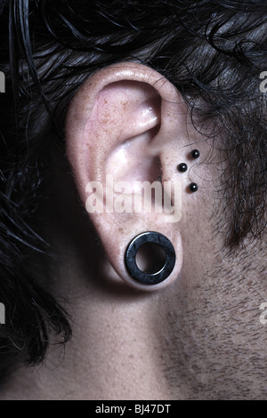 städtischen stilvolle kaukasischen Jüngling mit Ohrlöcher und piercing Studio-Porträt Stockfoto