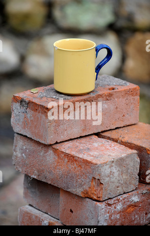 Ein Baumeister Becher Tee auf einem Stapel von aufgearbeiteten roten Ziegeln UK Stockfoto