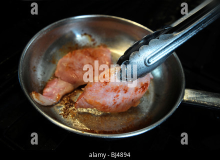 Zwei Speckscheiben Speck in einer Pfanne braten Stockfoto