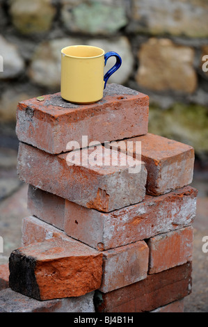 Ein Baumeister Becher Tee auf einem Stapel von aufgearbeiteten roten Ziegeln UK Stockfoto