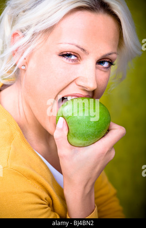 Junge Frau in Apfel beißen Stockfoto
