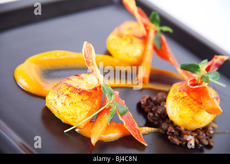 Trio von Jakobsmuscheln auf Curry Linsen, Butternut-Kürbis-Püree und knusprigem Parmaschinken Stockfoto