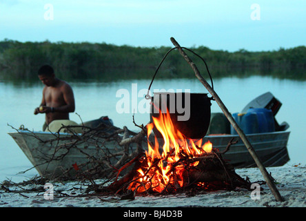 Mann und dem Schnellboot vor dem Lagerfeuer am Amazonas riverbeach Stockfoto