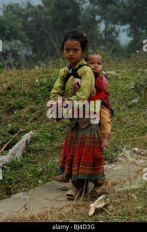 Minderheit Hmong Blumenmädchen tragen ihres Bruders, Lao cai, Can Cau, Nord-Vietnam Stockfoto