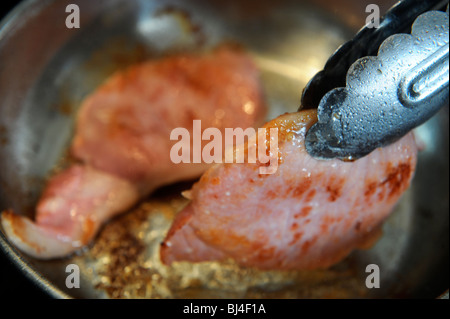 Zwei Speckscheiben Speck in einer Pfanne braten Stockfoto