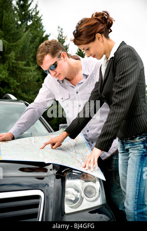 Junges Paar Blick auf einer Straßenkarte auf der Motorhaube eines Autos Stockfoto