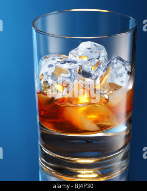 Glas Brandy mit Eiswürfeln auf einem blau isoliert