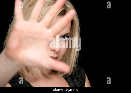 blonde Frau versteckt sich hinter der hand Stockfoto