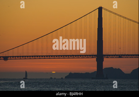 Sonnenuntergang hinter der Golden Gate Bridge und ein Segelboot, San Francisco, Kalifornien, USA Stockfoto