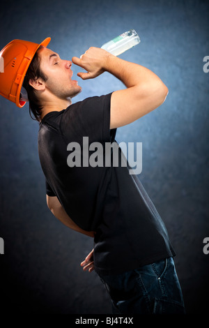 Betrunken Arbeiter mit Flasche. Auf dunklen Wand Hintergrund. Stockfoto