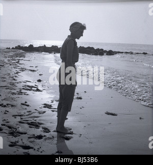 Modebewusste Frau am Strand in den 1950er Jahren. lächelnd, glücklich Sonne Mode starrte Ozean Atlantik am Strand Stockfoto