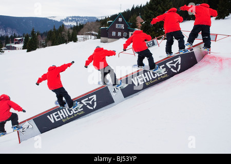 Mann Snowboarding, die Folge von vielen Schüssen. Ein Mann in einer roten Jacke ist Snowboarden auf einer Rampe. Bedeckt. Stockfoto