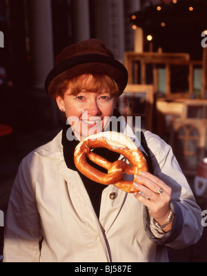 Junge Frau Essen Brezel, Alter Markt Weihnachtsmarkt, Köln (Köln), Nordrhein-Westfalen, Deutschland Stockfoto