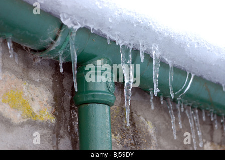 Schnee und Frost bauen auf diesem Gusseisen Dachrinne und Fallrohr.  Ohne Zweifel wird eine saftige Reparatur-Rechnung folgen Stockfoto