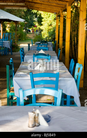 Griechisches Restaurant mit typischen blauen Stühlen im Schatten Stockfoto