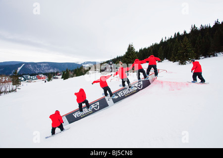 Mann Snowboarding, die Folge von vielen Schüssen. Ein Mann in einer roten Jacke ist Snowboarden auf einer Rampe. Bedeckt. Stockfoto